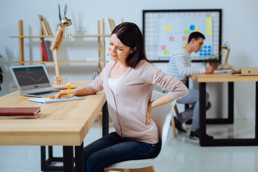 lugar trabajo mujer molesta haciendo muecas dolor tocando espalda mientras sentada posicion semi