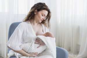 madre amamantando su bebe sentado sillon casa