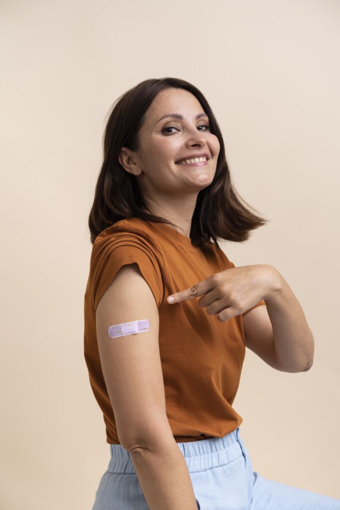 mujer sonriente mostrando pegatina brazo despues recibir vacuna